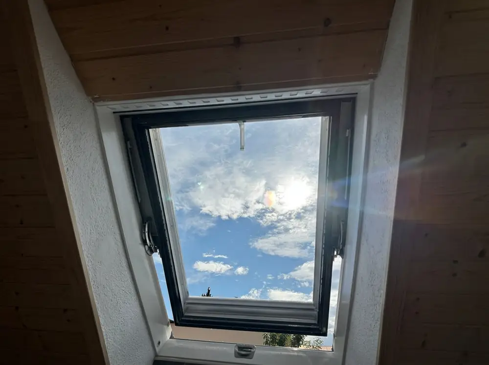 Pohľad zvnútra cez strešné okno na slnko a oblaky